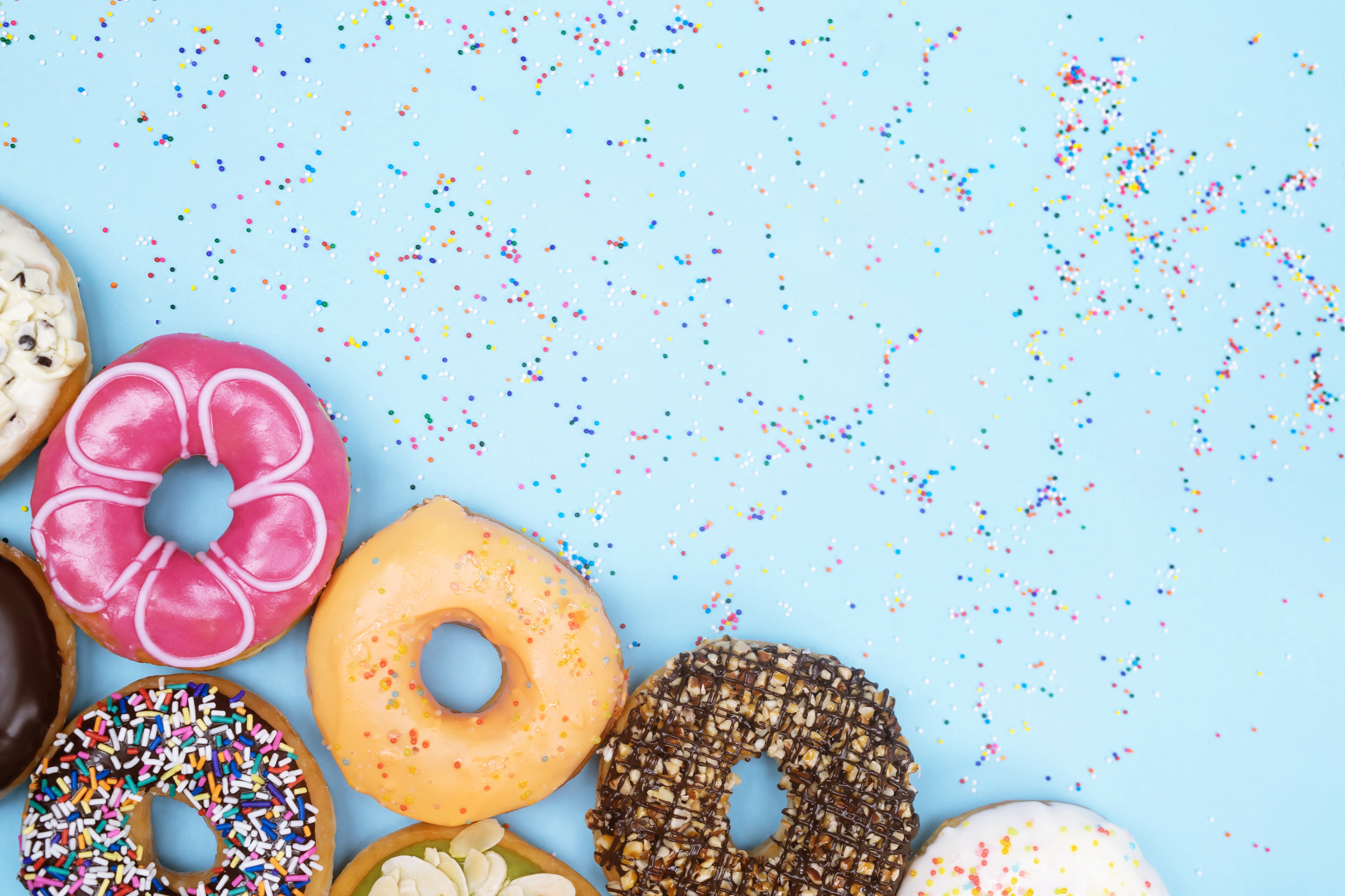 assorted donuts with chocolate frosting, topping sprinkles donuts Colorful variety and Variety of flavors mix of multi colored sweet donuts with frosted sprinkled on blue background. top view